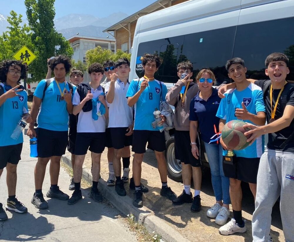 Equipo escolar celebrando junto a bus Marci Buses